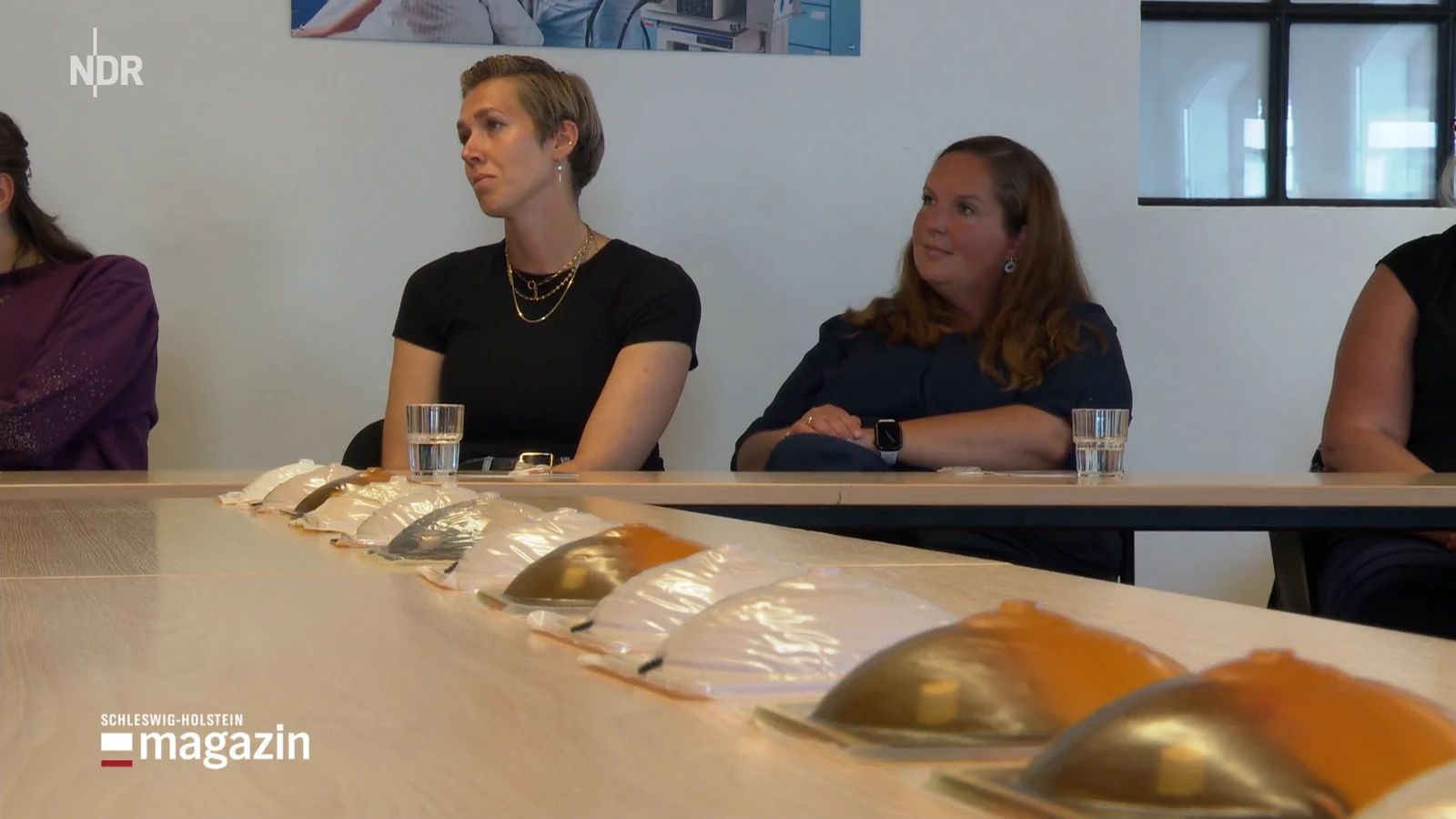 Women seated at a MammaCare breast self-exam workshop table lined with breast training models