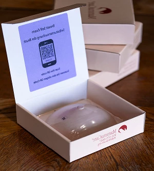 Open MammaCare BSE Kit box with a breast model inside and a QR code card in the lid